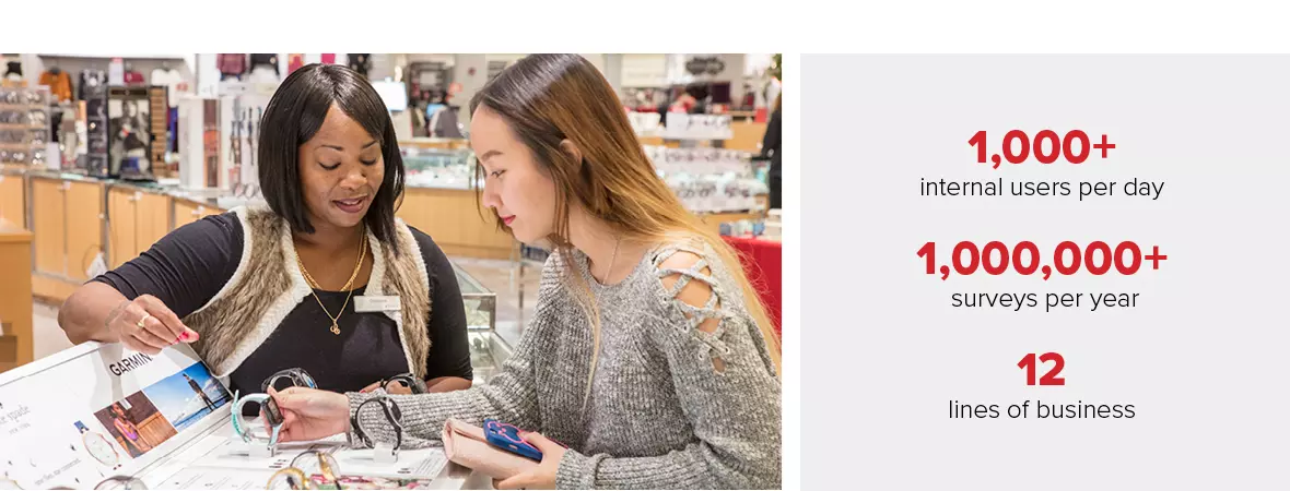 A photo of a Black, female sales associate with an Asian, female shopper looking at smart watches in the watch department.