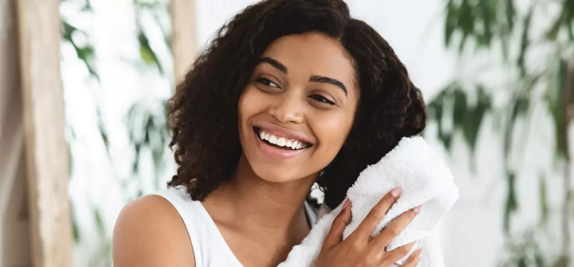 A smiling young woman towel-drying her hair.